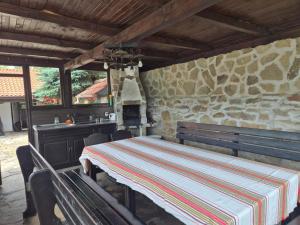 a dining room with a table and a stone wall at Къща Цачеви in Tryavna