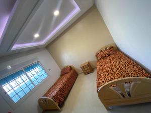 an attic room with two beds and a window at Ain grenz in Kelibia