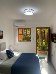 a bedroom with a blue bed and a window at InnFloripa - Pousada no Campeche 7 min do Aeroporto in Florianópolis