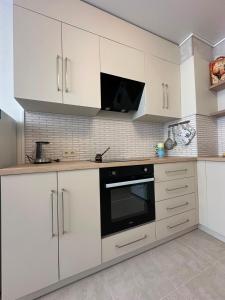 a kitchen with white cabinets and a black oven at квартира in Odesa