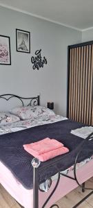 a bed with a black and pink blanket on it at Apartament Różowa Perła in Przemyśl
