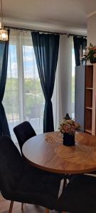 a dining room table with chairs and a large window at Apartament Różowa Perła in Przemyśl +7 photos