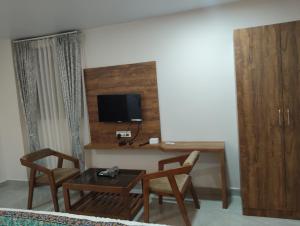 a living room with a desk with a tv and chairs at Hotel shivam comfort in Hubli