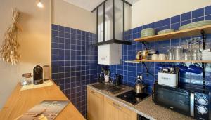 a kitchen with blue tiles on the walls and a counter at TERRASSE Vue MARINA - PARKING Privé - Port Commerces & PLAGE à PIED - Vue Exceptionnelle - RétroMirabeau "Côté Mer" in Gruissan
