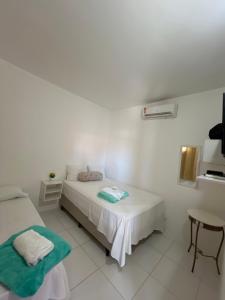 a white room with a bed and a table at Kitnet em Santo Antônio in Mata de Sao Joao