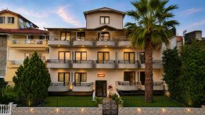 a large building with a palm tree in front of it at Jason Apartments in Paralia Katerinis