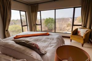 a bedroom with a bed and a chair and a window at Sweet Zebula in Mabula +21 photos