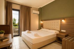 a bedroom with a large bed and a balcony at Jason Apartments in Paralia Katerinis