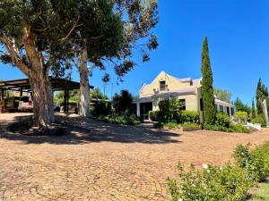 a house with a tree and a brick driveway at UnderHill Farm in Klipkraal