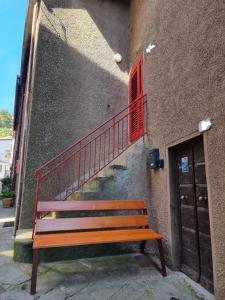 a wooden bench sitting next to a building with a staircase at La Roccia Rossa in Stribugliano