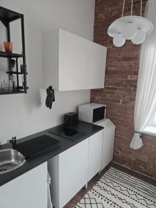 a kitchen with white cabinets and a brick wall at Kuninga Apartment in Old Town with Free Parking in Pärnu