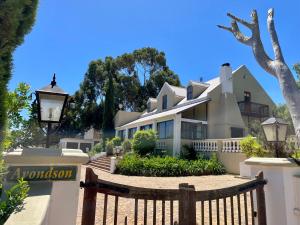 a large white house with a wooden fence at UnderHill Farm in Klipkraal
