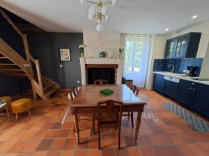 a dining room with a table and a fireplace at La Glycine, Maison au calme avec jardin, Fibre Wi-Fi, 20 min des plages, Parking privé in Luçon