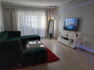 a living room with a green couch and a tv at Cousy Corner in Roodepoort