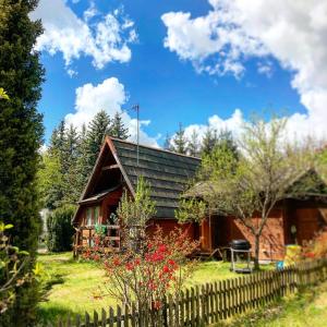 a wooden house with a fence in front of it at Tleniowo Domek in Tleń