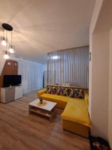 a living room with a yellow couch and a television at M & A Apartmani in Kumanovo