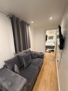 a living room with a gray couch and a television at M18 Escape in Havering atte Bower