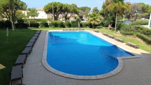 a large swimming pool with benches around it at Sol Apartments in Vilamoura