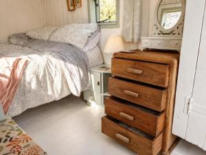 a small bedroom with a bed and a dresser at Mabel the Steam Roller Caravan at Rosuick Organic Farm in Saint Martins Green +3 photos