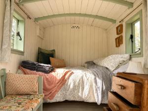 a bedroom with a bed and a chair in it at Mabel the Steam Roller Caravan at Rosuick Organic Farm in Saint Martins Green