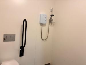 a bathroom door with a shower nozzle and a toilet at Mabel the Steam Roller Caravan at Rosuick Organic Farm in Saint Martins Green