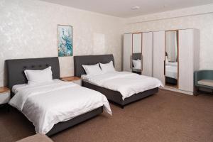 a bedroom with two beds and a mirror at Gulshan Hotel in Urganch