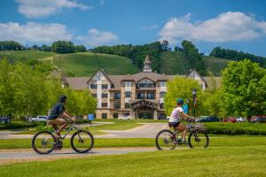 two people riding bikes down a road in front of a house at Boyne Mountain Resort in Boyne Falls