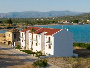a white building with a red roof next to the water at Latsis Suites in Plytra