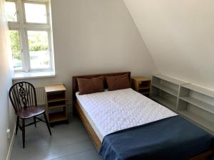 a small bedroom with a bed and a chair at Lilla Skolhuset i Ingelsträde in Höganäs