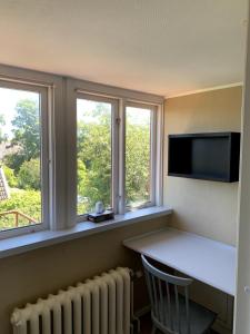 a room with two windows and a desk and a tv at Lilla Skolhuset i Ingelsträde in Höganäs +6 photos