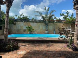 a swimming pool with a patio and palm trees at Pousada Kalangoo in Barra Grande