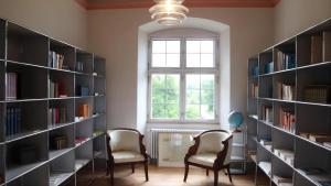 a library with two chairs and bookshelves at Bodensee-Schloss Maurach in Uhldingen-Mühlhofen