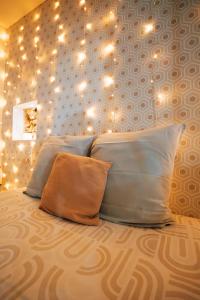 a bed with three pillows and lights on the wall at Ancien Cloître rénové - Hyper centre - T2 de 50m2 in Mont-de-Marsan