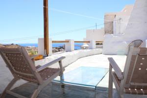 a pair of chairs and a glass table on a balcony at NeSi Cycladic Living in Ano Syros