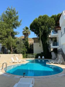a swimming pool with chairs and a building at Double Comfort Marmaris in Marmaris