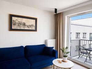 a living room with a blue couch and a balcony at Penthouse21 in Oświęcim