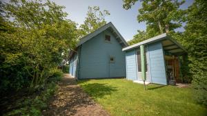 a blue house with a yard next to a building at Vakantiewoning Vrijburg in Schagerbrug