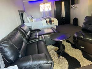 a living room with a leather couch and a bed at One love suites in Mokopane