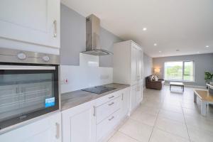 a kitchen with white cabinets and a living room at 3 Bedroom Duplex Apartment By Travel Lets Short Term Rental Agency Donegal Town in Donegal