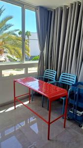a red table and chairs in a room with a window at Ocean View Studio in Playa del Ingles in San Bartolomé