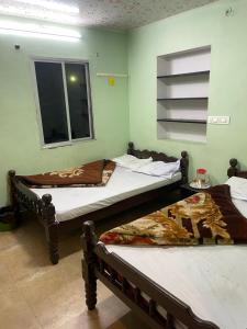 two beds sitting in a room with a window at Tvkhomestay in Vālpārai