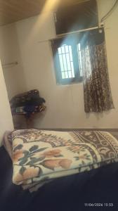 a bed in a room with a window and a bedspread at Tvkhomestay in Vālpārai
