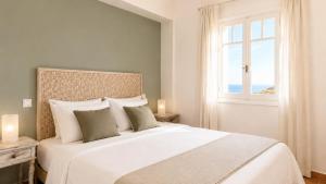 a bedroom with a large white bed with a window at Yakinthos Suites in Mykonos +66 photos