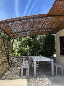 a picnic table and bench under a straw roof at Jasmin et Camomille in Roquebrun