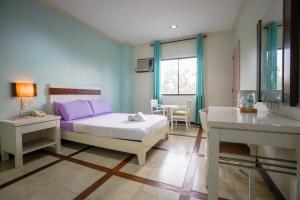 a bedroom with a bed with purple pillows and a table at The Inns Bacolod in Bacolod