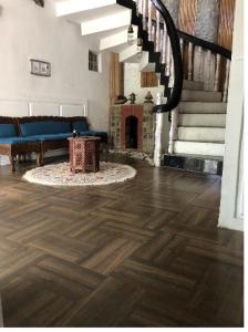 a living room with a wooden floor and a fireplace at Rooebarpur in Khāniyār