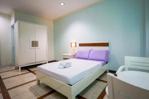 a bedroom with a white bed and purple pillows at The Inns Bacolod in Bacolod +16 photos