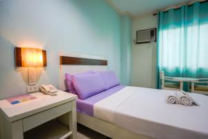 a small room with a bed and a desk and a bed sidx sidx sidx sidx at The Inns Bacolod in Bacolod