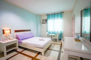 a bedroom with a bed and a table in it at The Inns Bacolod in Bacolod