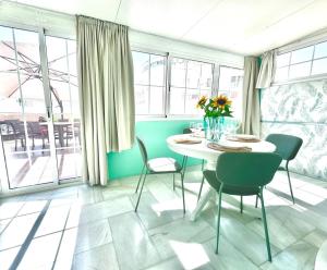 a dining room with a table and chairs and windows at The Bajondillo terrace in Torremolinos